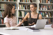 © fizkes - Mentoring at high school. Attentive student girl sit at desk in university library listen to smart female classmate friend explaining new topic helping understand difficult material expressing opinion