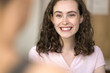 © fizkes - Pleasant conversation. Cropped portrait beautiful young lady with long curly hair talking with blurred person indoors hold nice dialogue enjoy discussion listen to partner with white smile. Copy space
