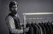 © Yevhen - Portrait of a young bearded guy, in a men's clothing store chooses a business suit for work. Man match his suit in custome made garment fashion boutique. Tailor, tailoring. Black and white