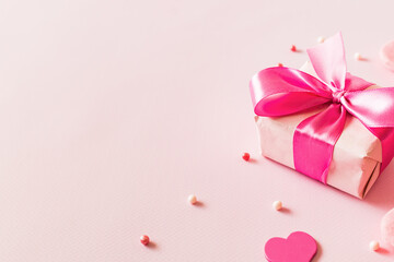 Wall Mural - Pink hearts and gift box with ribbon on a light pink background