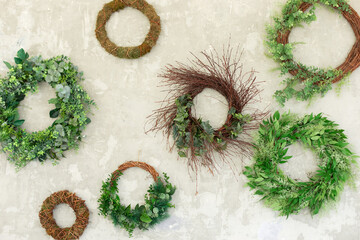 Wall Mural - Green wreaths with leaves on grey wall. Wreath made of branches. Flowers composition. Boxwood wreath. Green olive wreath. Floral round frame made of branches. Wedding wall decoration made of circles.	