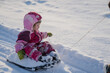 © K - Small three year old happy baby girl being pulled in snow sled in white snow having fun and great winter fun
