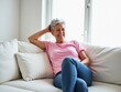 © TimeaPeter - Cheerful Senior Woman Relaxing on White Couch in Bright Modern Living Room