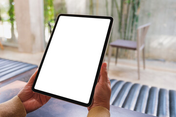 Wall Mural - Mockup image of a woman holding digital tablet with blank desktop screen in cafe