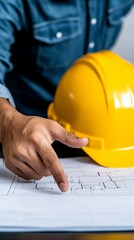 A construction worker reviews blueprints, pointing out a detail.  Safety helmet rests nearby.