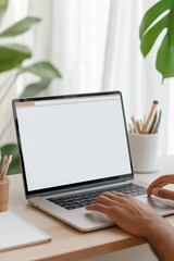 a person is typing on a laptop in front of a potted plant. the laptop screen is blank, and the perso