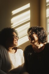 Wall Mural - Two women are smiling at the camera. One of them is wearing glasses. Scene is happy and friendly