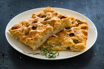 Wall Mural - Focaccia alle olive - foccacia with green olives, garlic and rosemary on black background