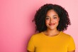 © SerPak - Young african female smiling against pink background in yellow shirt.