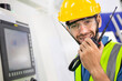 © winnievinzence - Portrait of male worker talking on radio phone or walkie-talkie with colleague to controlling work in front of industry machine at industrial factory. technology and communication at workplace