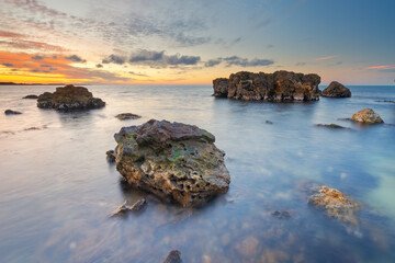 Wall Mural - beautiful nature seascape of beach shore among rocks on evening sunset.