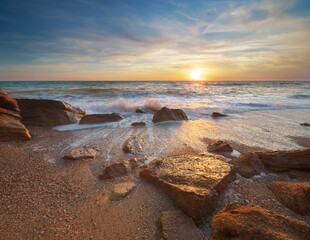 Wall Mural - stones and sea during the sunset. beach shore among rocks and stones on evening sunset.