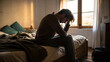 ©  Princess Turandot - Man sitting on bed in dimly lit room holding head in hands feeling stressed and anxious