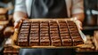 © tono boys - Baker holding tray of chocolate brownies.