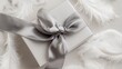 © -Quantum Pixels- - Elegant gift box adorned with gray satin ribbon and white feathers for a serene holiday composition on a neutral background with copy space
