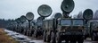 © adiba - A line of military vehicles with radar dishes, parked on a dirt road.