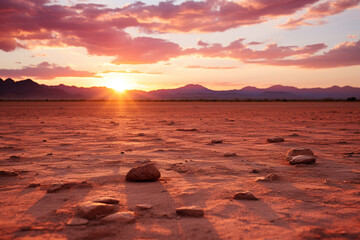 As sun emerges over horizon, it illuminates desert landscape, creating a picturesque scene with pink and golden hues in sky and a comforting radiance on sandy terrain