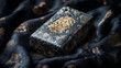 © Prapat - Black antique book with ornate golden embossed pattern on leather cover placed on dark black silk fabric with elegant folds and dramatic shadows