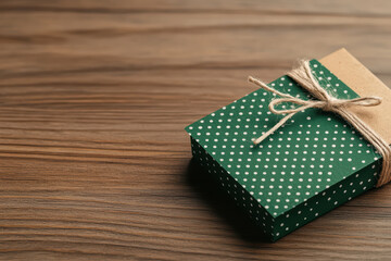 Green polka dot gift box tied with twine on wooden surface