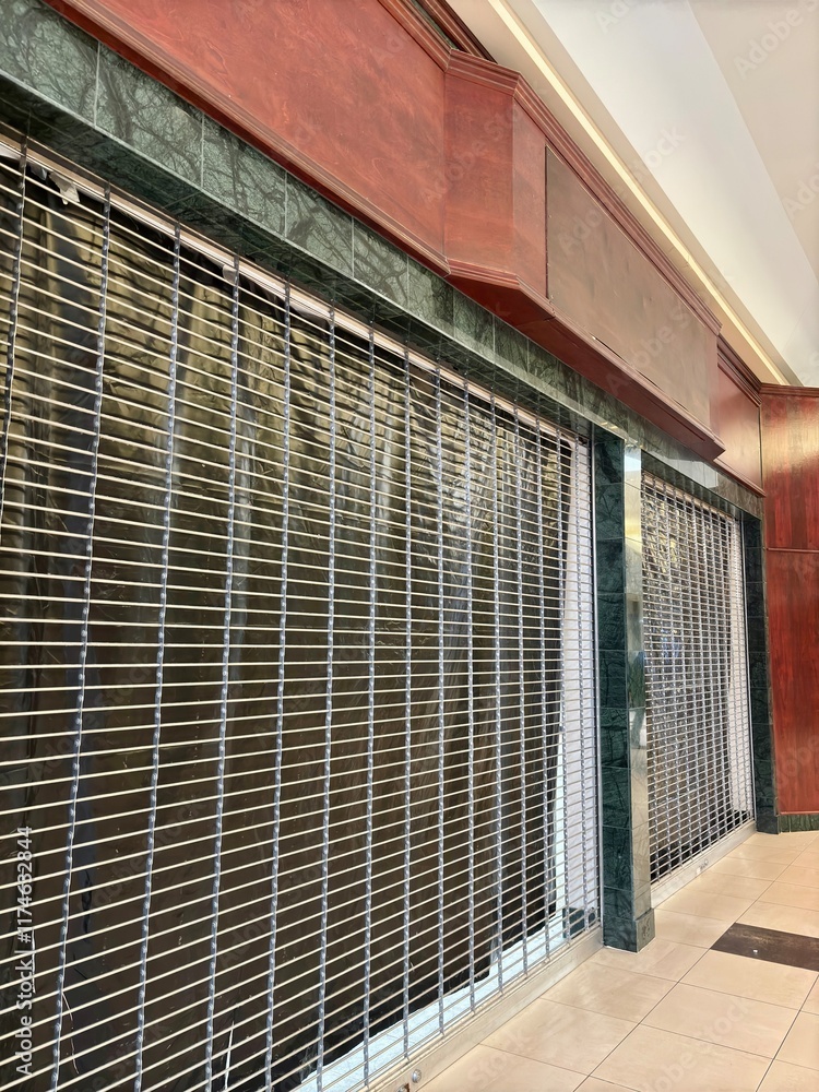 Shuttered Storefront Shuttered storefront with metal security grille at dead shopping mall ...