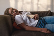 © Cavan - Pretty woman napping on the sofa in her living room after reeding book