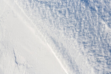 Wall Mural - beautiful winter background with snowy ground. natural snow texture. wind sculpted patterns on snow 