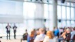 © Jo - A blurred image of a large conference hall with attendees and speakers engaged in a business event.