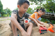 © themorningglory - Adorable kindergarten kids boy and girl enjoy play car truck toy on sand outdoor activity