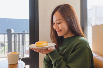 Poster - Portrait of a young woman holding a plate of donut in cafe