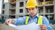 © Vitaliy - Worker with plans at a construction site with scaffolding