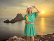 © Ljupco Smokovski - Woman in a green dress holding a glass of cocktail on a cliff in Ibiza