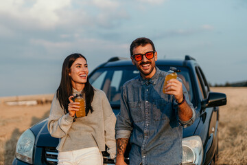 Wall Mural - Couple enjoying the simple joys of life: pizza, a car, and a breathtaking sunset in a meadow