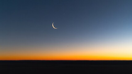 Wall Mural - a thin crescent moon hangs in the darkening twilight sky above a vibrant orange sunset. ideal for se