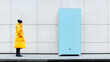 © Александра Ходорковс - Woman in yellow coat examining large blue sculpture against minimalist urban wall
