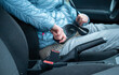 © AnastasiiaAkh - Close-up of a woman fastening her seat belt inside a car. Safety awareness and travel preparation concept