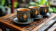 © vina - Three ornate tea cups on a wooden tray, surrounded by greenery, suggesting a serene tea experience.