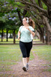 © Javier - Mujer entrenando, trotando y sonriendo en un parque urbano en un hermoso día soleado. Mujer feliz corriendo mientras escucha música