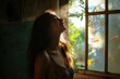 © Fightstar - Young woman standing by open window with sunlight and breeze