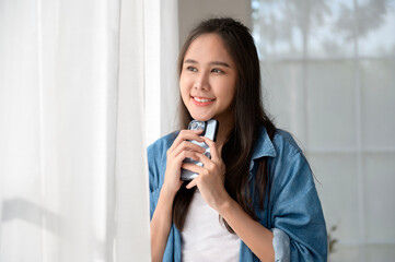 Wall Mural - Young Asian woman enjoy using smartphone at home