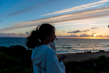 Wall Mural - MUJER JOVEN MORENA 21 AÑOS POSANDO PUESTA DE SOL EN EL MAR EN CÁDIZ 2025