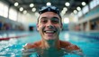 © natakot - A young man with a bright smile emerges from the water, showcasing his enthusiasm for swimming. His swim goggles rest on his forehead, capturing the essence of joy and determination in a vibrant