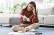 © KMPZZZ - Business financial concept, stressed asian young woman hand checking list with bill for calculate accounting expense credit card payment on due deadline, trying to find money to pay debt on table.