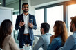 © Viktor - Indian businessman leads professional development session for team members in office. Group listens attentively to presentation. Business meeting workshop setting. Modern office space. Business