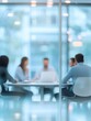 © Business Pics - A blurred office meeting with business people sitting around a table, engaged in a discussion or training session. Blurred office and workplace background.