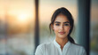 © NaphakStudio - Confident Indian woman with glowing skin, standing indoors at sunset. Her expression reflects determination and poise, showcasing professional demeanor.
