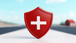 © JK_kyoto - Red safety shield icon with white cross symbol on blurred background