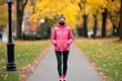 © Panithi - Young Woman in Pink Jacket Walking in Autumn Park Pathway