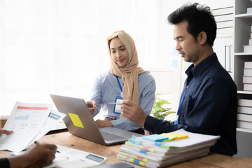 Wall Mural - Collaborative Brainstorming: A diverse team of business professionals huddle around a laptop, engaging in a lively discussion, their focus on achieving a shared goal.