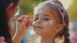 © OLEKSANDR - Little girl getting her face painted by face painting artist.