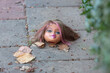 © Westend61 - Discarded doll's head with tangled hair lying on sidewalk